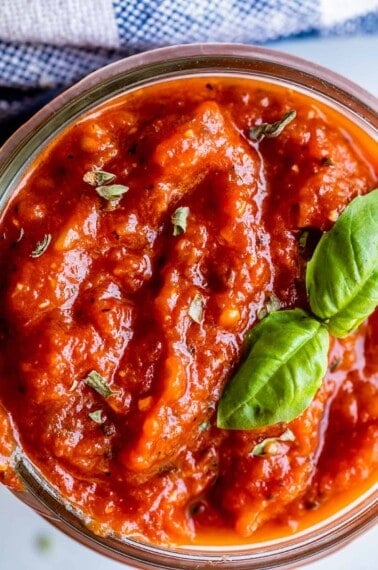 best pizza sauce in a mason jar with basil and oregano garnish