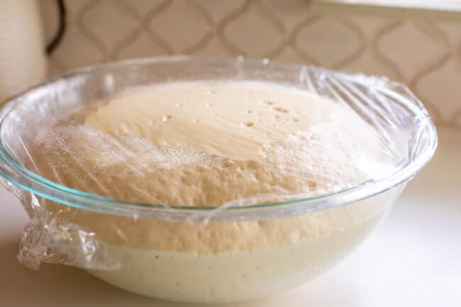 pizza dough rising in a glass bowl.