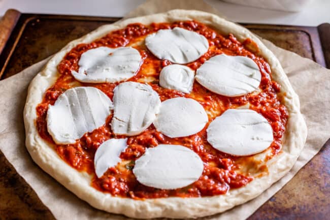 slices of mozzarella cheese on a raw pizza