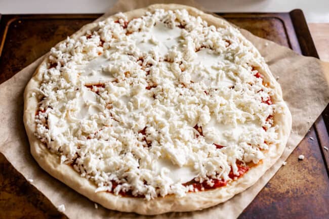 raw pizza dough with sliced and shredded mozzarella on top