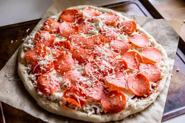 rolled out pizza dough topped with sauce, cheese, and pepperoni