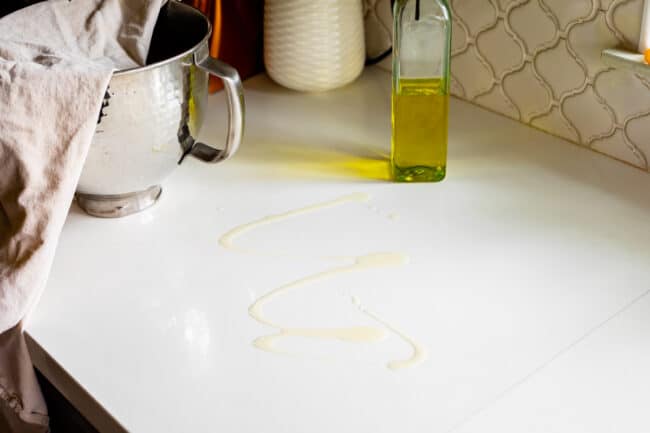oil drizzled on white countertop to roll out pizza