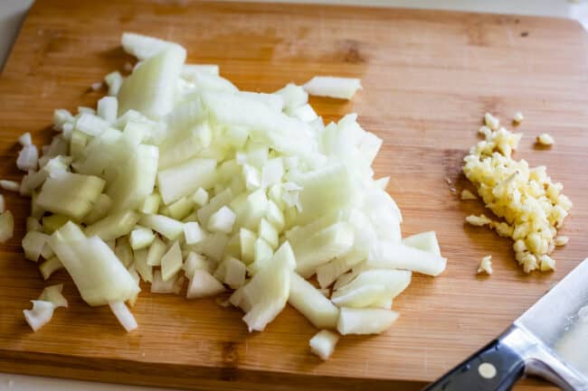 onions and garlic on a cutting board chopped.