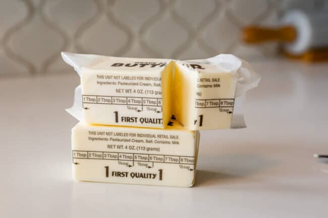 stick of butter on a counter with another stick on top cut in half