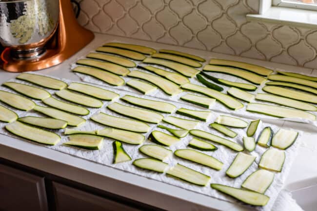 sliced zucchini laid out on paper towels to absorb water.