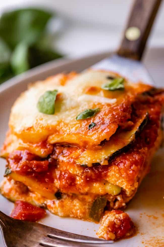 zucchini lasagna recipe being placed on a plate with a spatula.