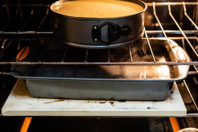 cheesecake in oven with boiling water in pan on a lower rack.