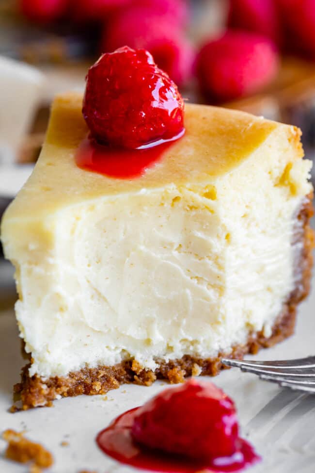 a bite taken out of easy cheesecake with raspberries on top.