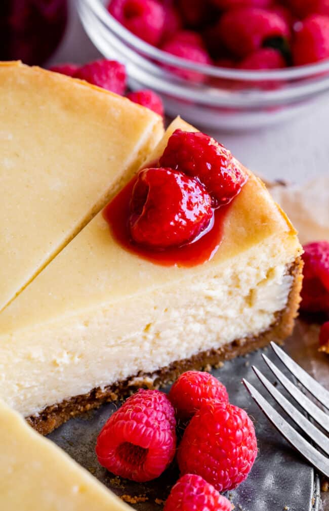 classic cheesecake in a pan with raspberries.