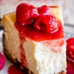 classic new york cheesecake with a bite taken out and raspberries