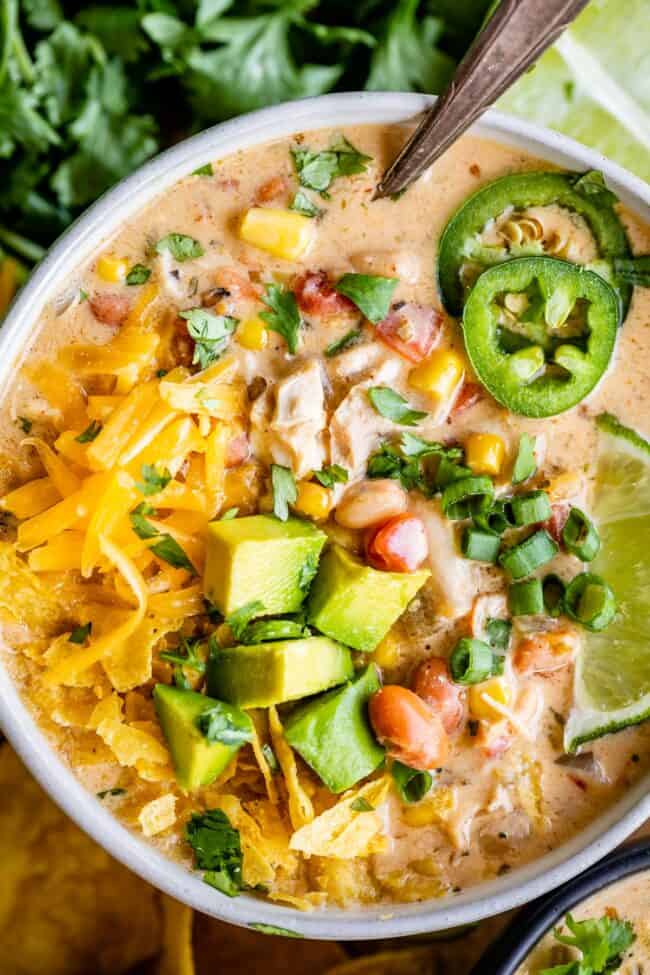 white chicken chili in a bowl on a wooden board with jalapenos.