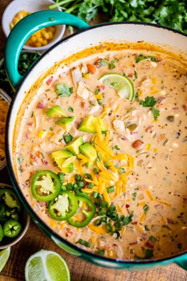 chicken and white bean chili in a pot with jalapeno and cheese garnishes.