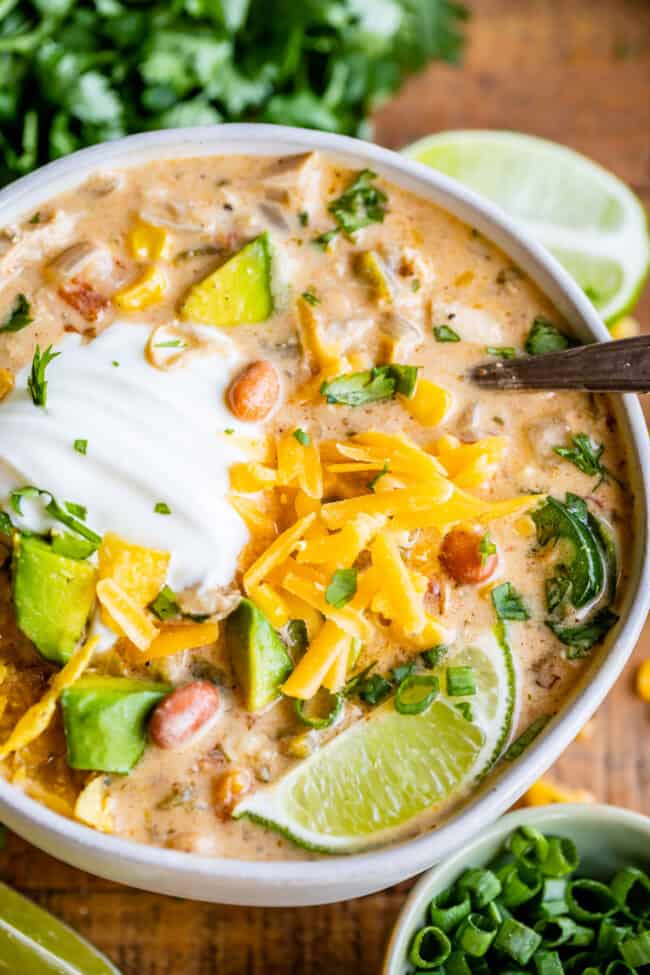 creamy white chicken chili in a large bowl with sour cream and lime and spoon.