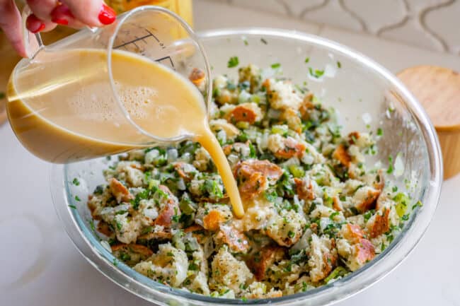 pour broth into a bowl of bread and herbs