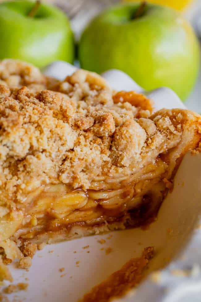 crumble top Dutch apple pie in a white pie plate shot from the side.
