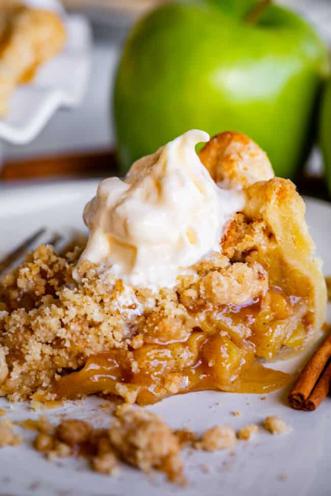a slice of Dutch apple pie on a plate with cinnamon sticks and vanilla ice cream.