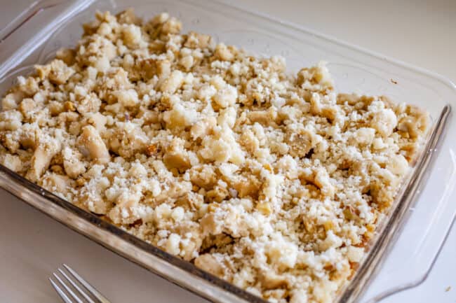 topping a pan of pumpkin pie bars with streusel