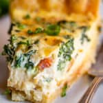 spinach quiche on a plate with a bite taken out