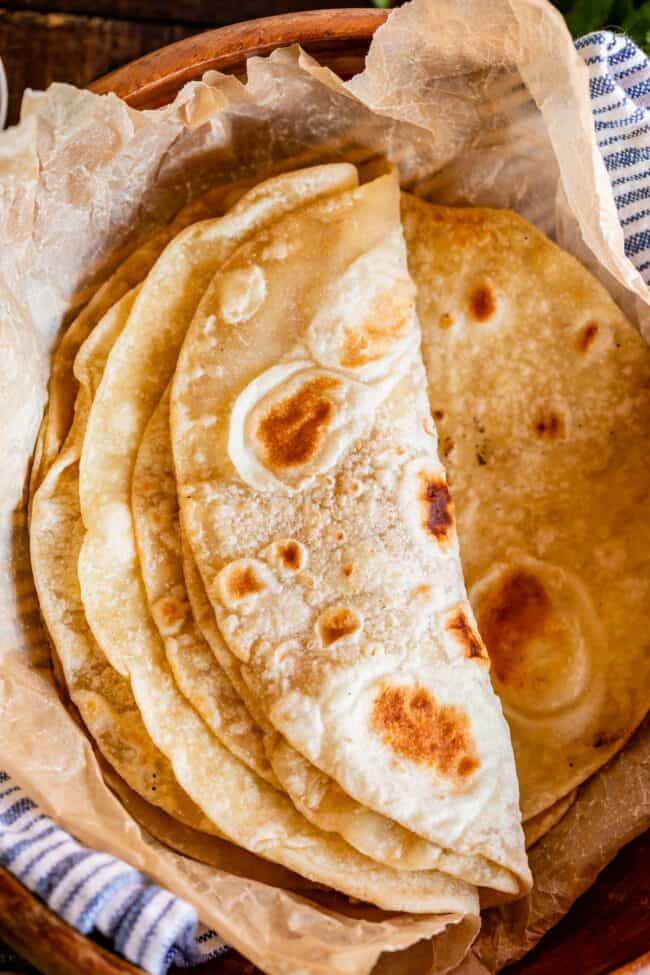 roti bread stacked in a wooden bowl with parchment paper.