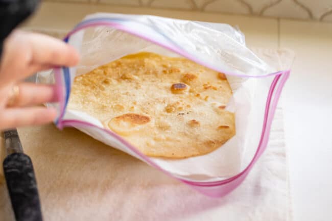 roti bread steaming in a ziplock bag with paper towels.