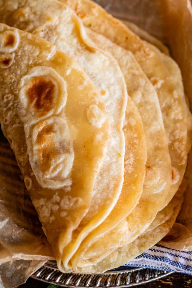 Indian bread stacked and folded over on a metal plate with blue napkin.