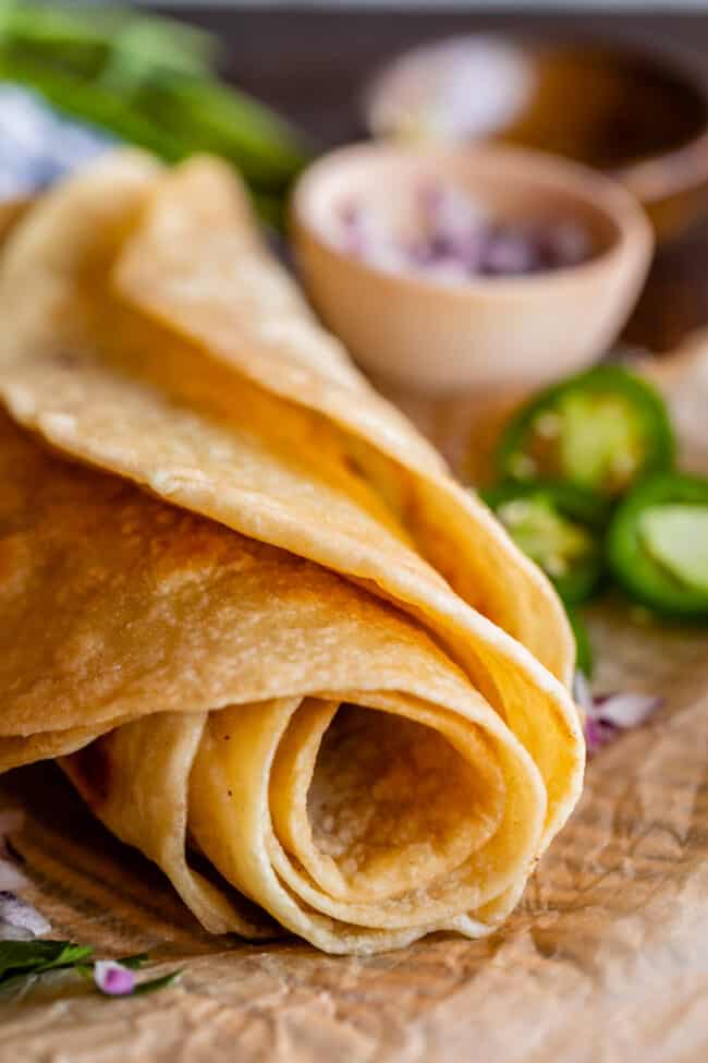 rolled up Indian flatbread on parchment paper with jalapeno and red onion.