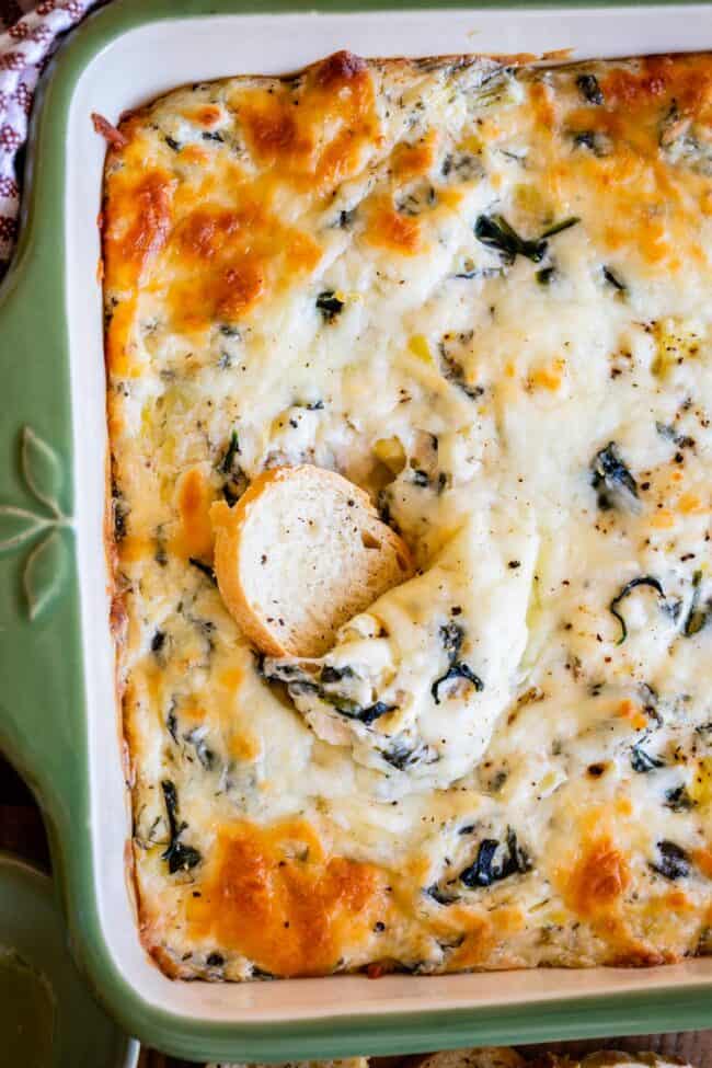 bread slice scooped into center of pan of spinach artichoke dip recipe