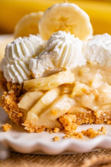 slice of easy banana cream pie on a plate topped with whipped cream