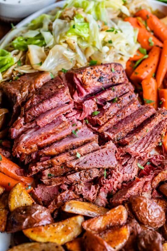 corned beef recipe, sliced on a platter with potatoes, carrots, and cabbage