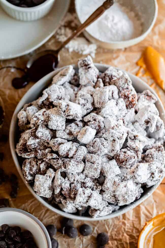 a large bowl of puppy chow recipe chex garnished with melted chocolate and peanut butter.