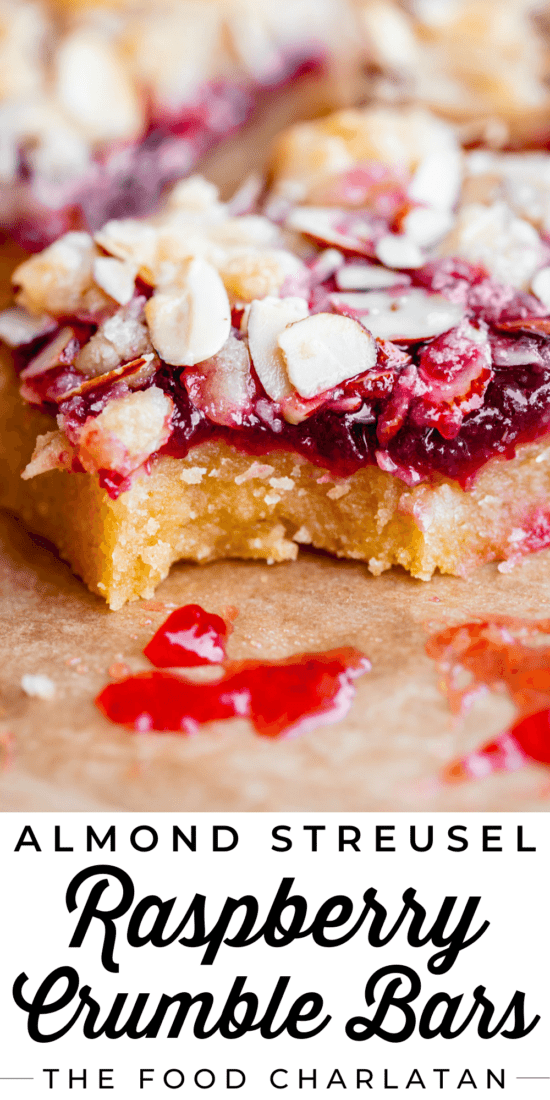 a bite taken out of raspberry crumb bar with almond topping.