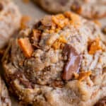 butterfinger bits cookie recipe with more crushed butterfinger on the pan.