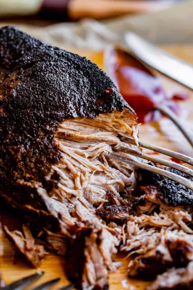 crock pot pulled pork with blackened edge being shredded with a pork.