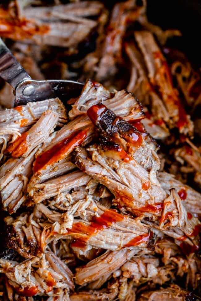 spoon lifting shredded pork with bbq sauce.