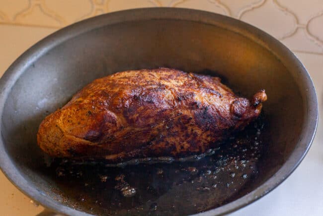 searing pork shoulder in a skillet.