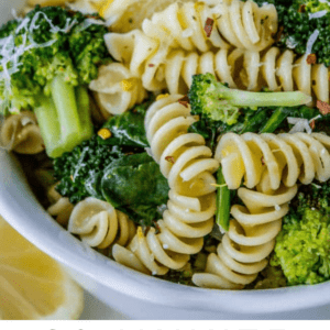 rotini pasta and broccoli in a white bowl with lemon.