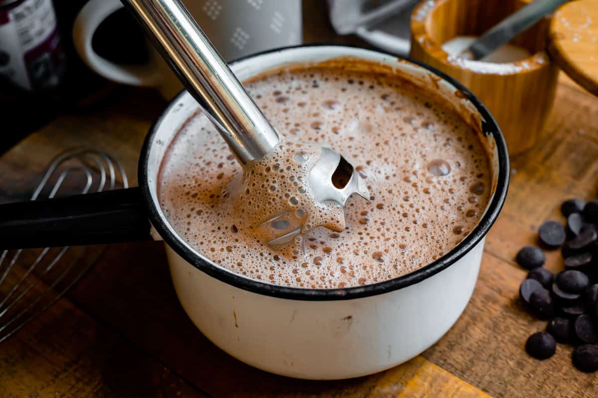 an immersion blender in a pot full of hot chocolate.