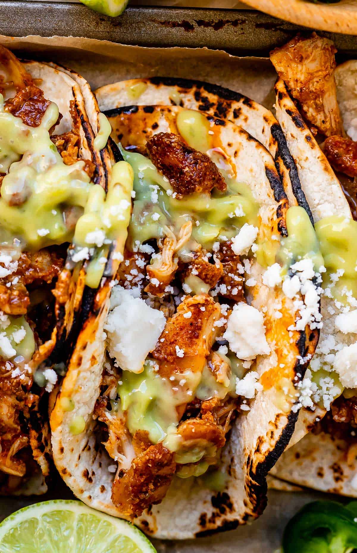close up of a single shredded chicken taco with juicy meat, cotija cheese, and green salsa.