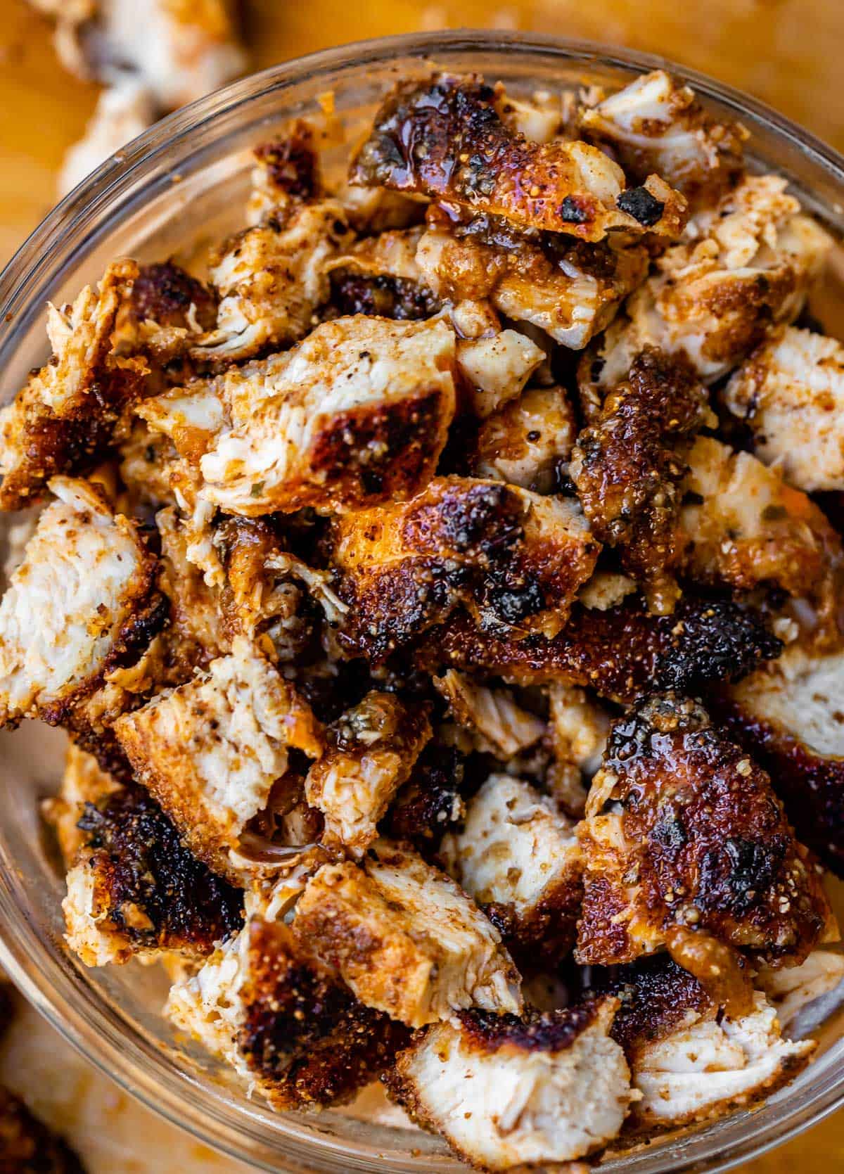 a glass bowl filled to the top with chopped, cooked chicken that is seasoned well.