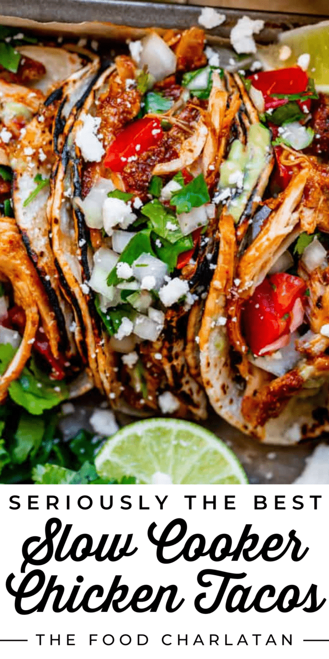 Shredded Chicken tacos on a tray with tomatoes, onions, cilantro, and cheese.