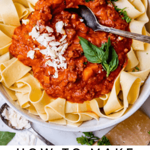 bowl of pappardelle noodles with red sauce and basil and spoon.