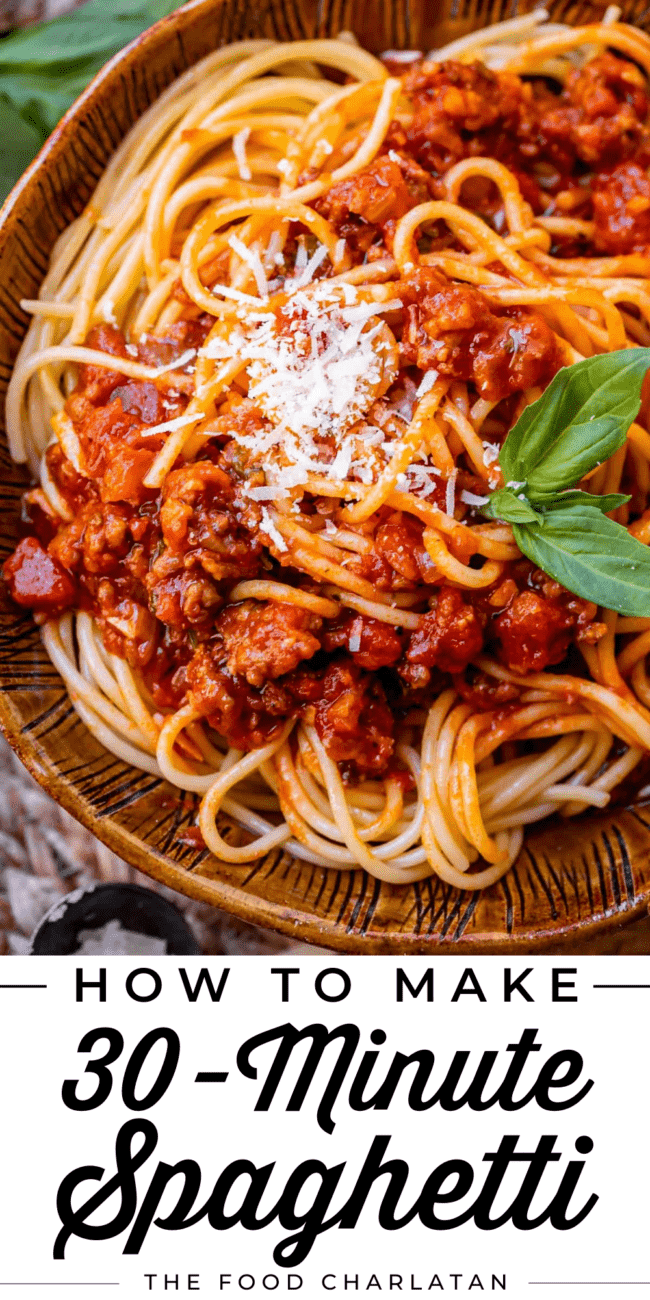 spaghetti sauce with noodles in a brown bowl with parmesan and basil.