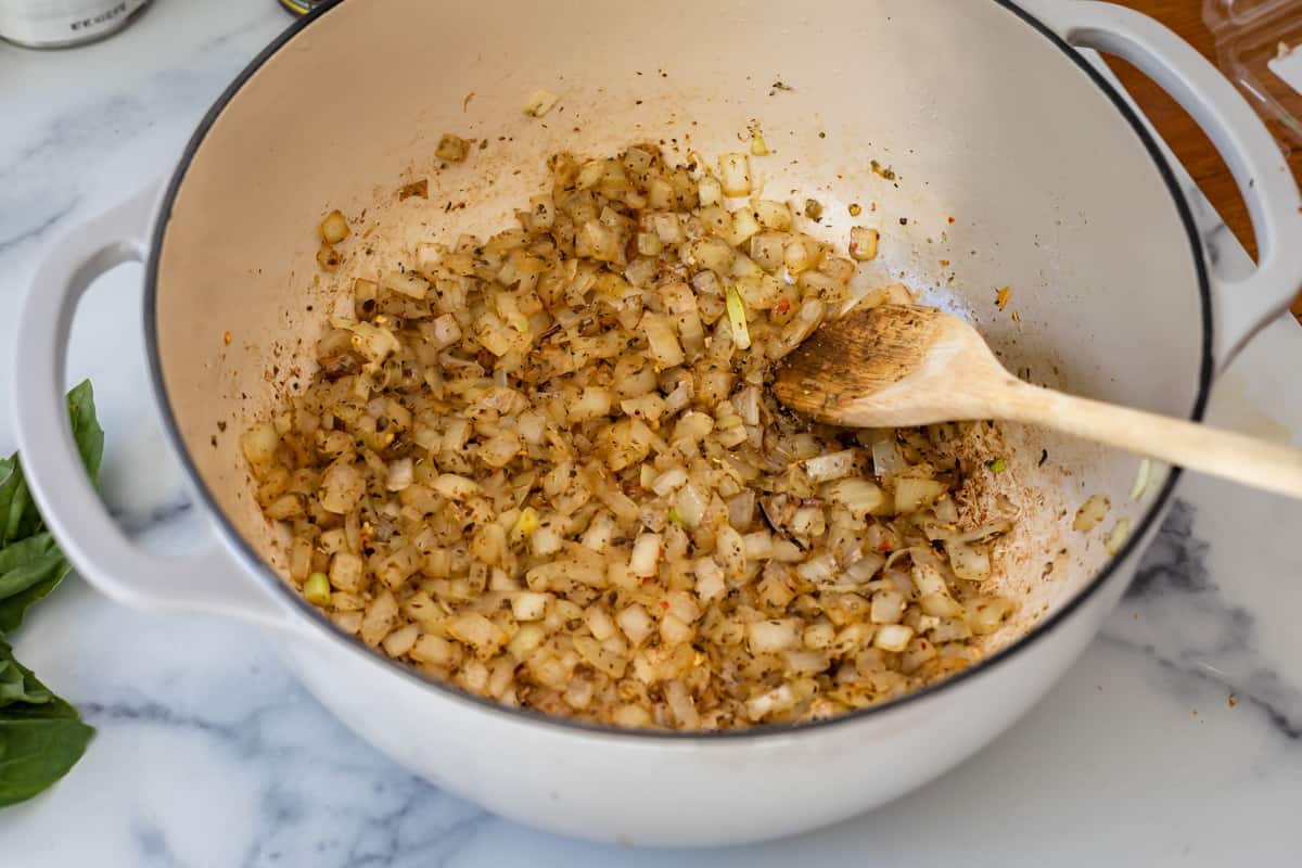 chopped onion browned in a ceramic bowl with seasonings for spaghetti meat sauce.