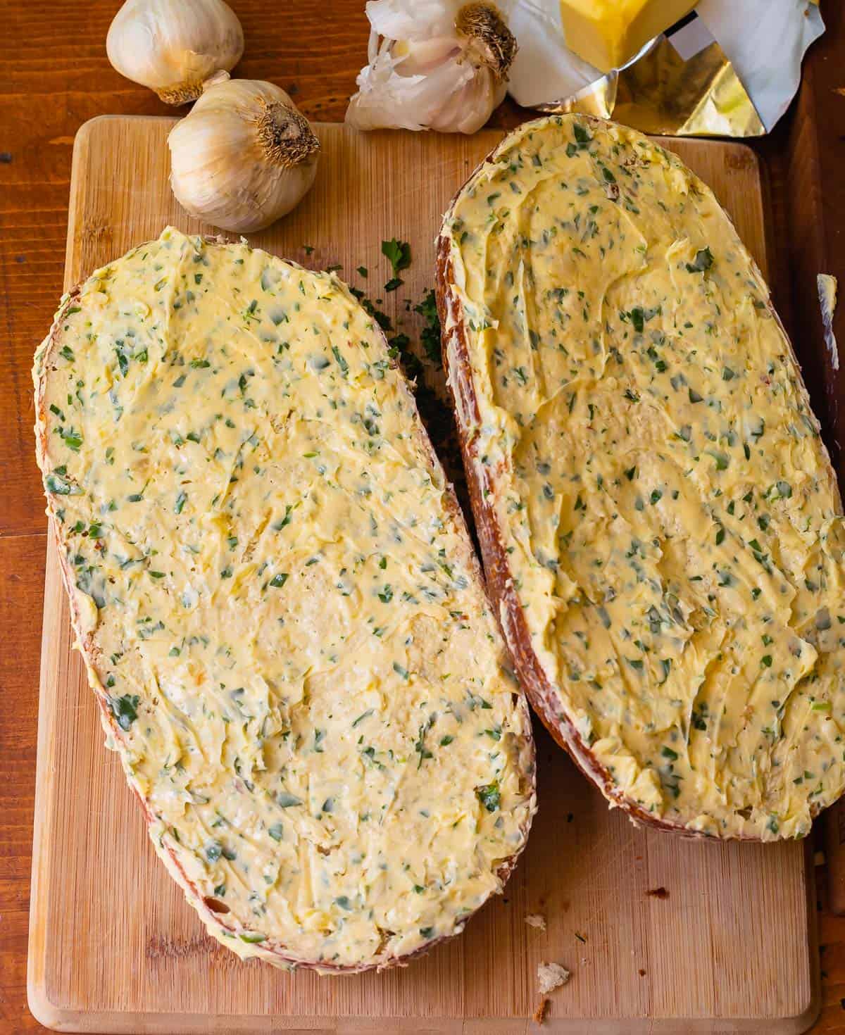 lengthwise split loaf of unbaked garlic bread showing just how much (a lot) of butter to use.