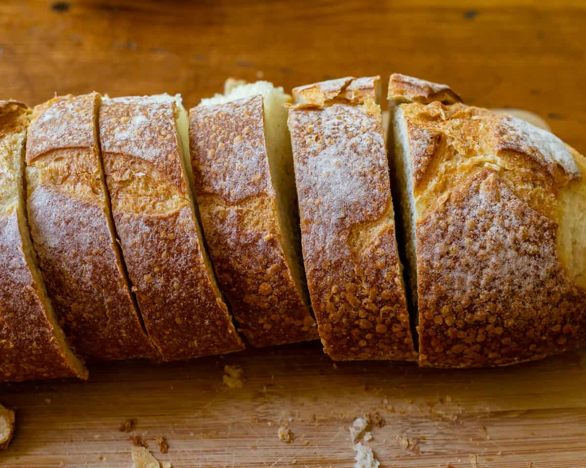 loaf of bread sliced into 1 inch slices on a cutting board.