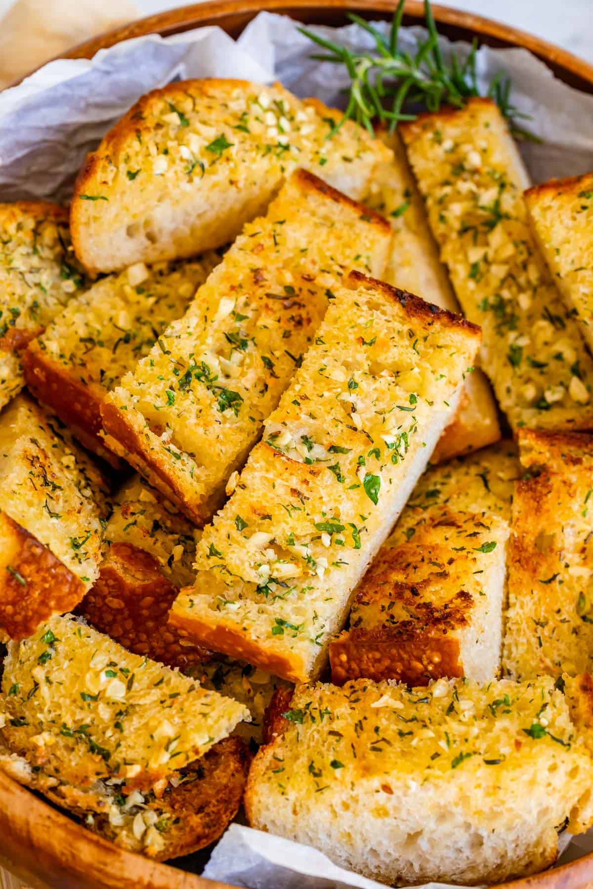 garlic bread recipe for crispy garlic bread, sliced and piled in a wooden bowl.