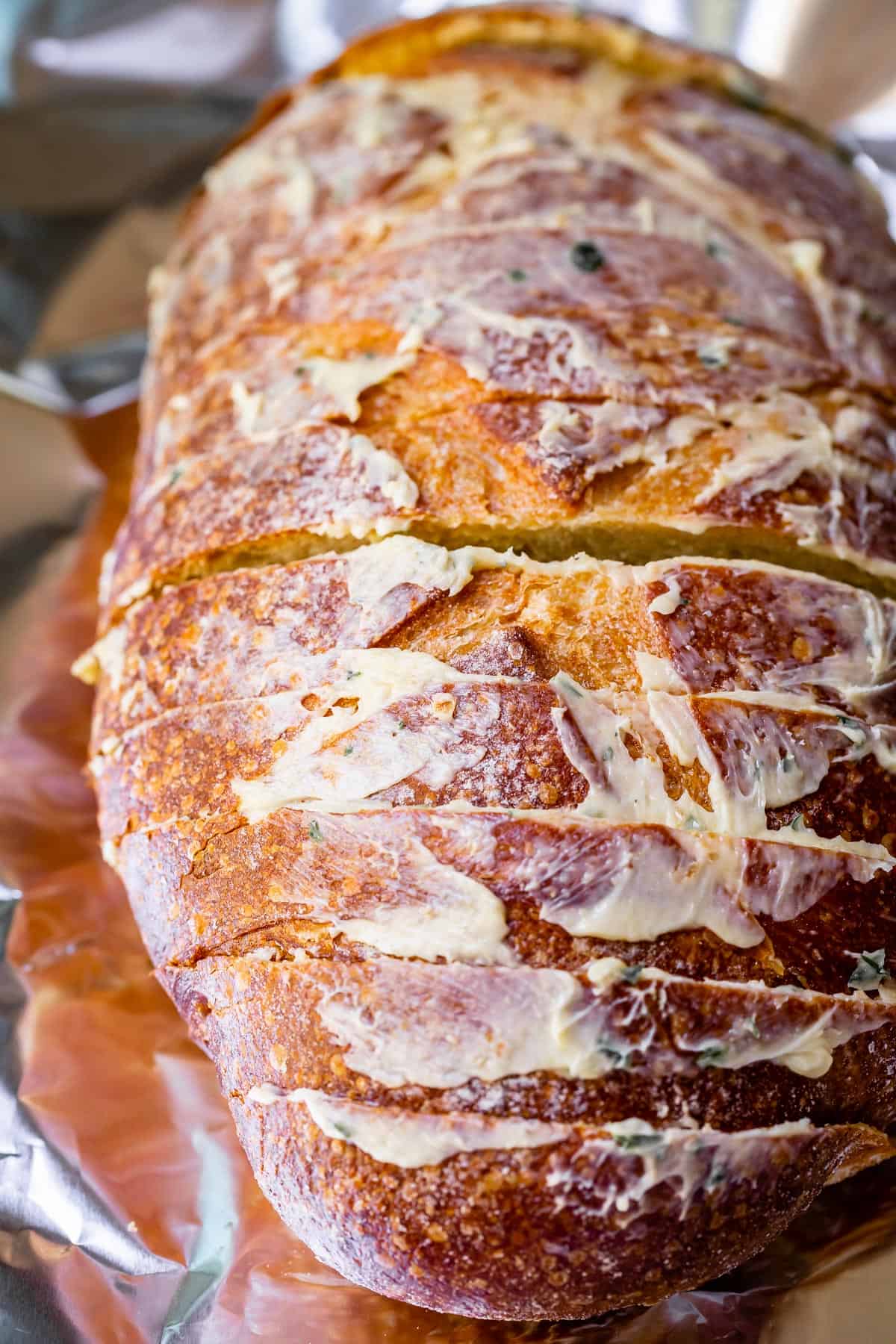 sliced crusty bread in loaf form with homemade garlic butter spread right on the top crust.