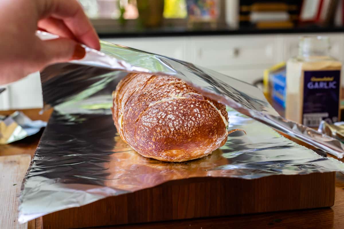 a loaf of sliced homemade garlic bread on foil about to be wrapped for the oven.