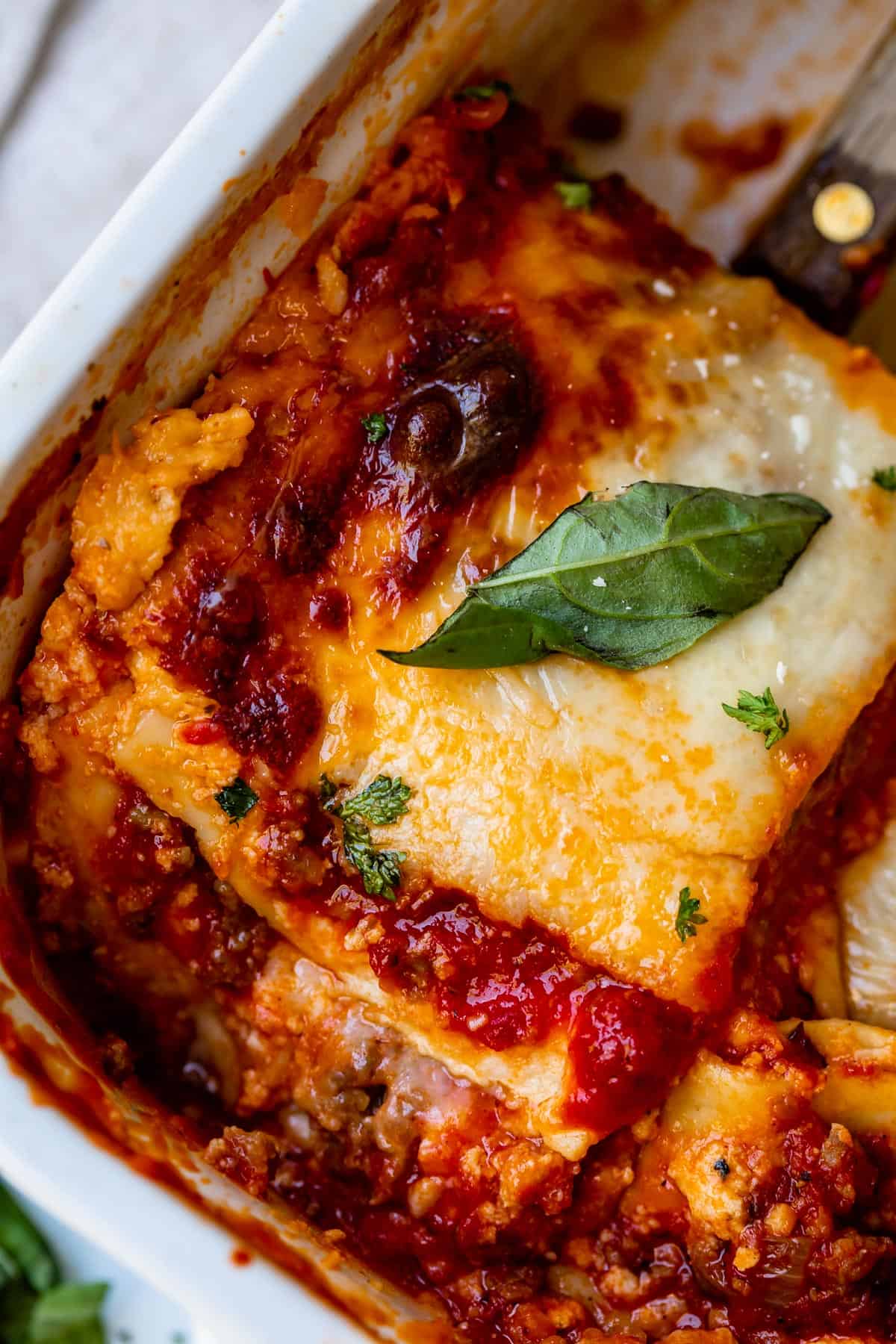 overhead shot of a slice of sausage lasagna with ricotta and topped with basil.