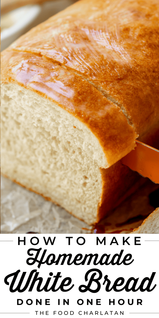 a bread knife carefully cutting a thick slice from a whole loaf of homemade white bread.